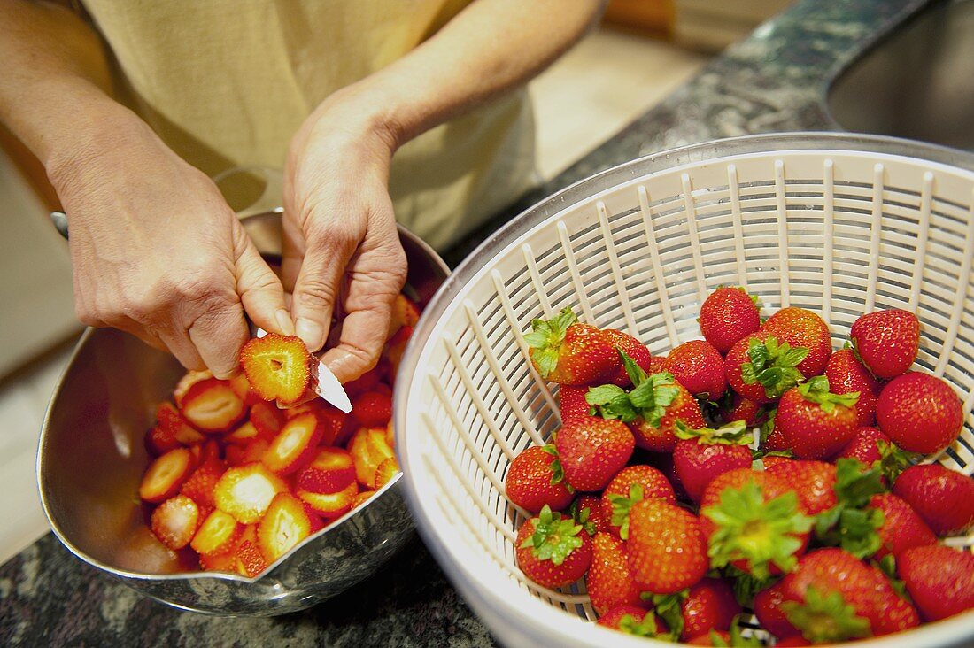 Frau schneidet Erdbeeren in Scheiben