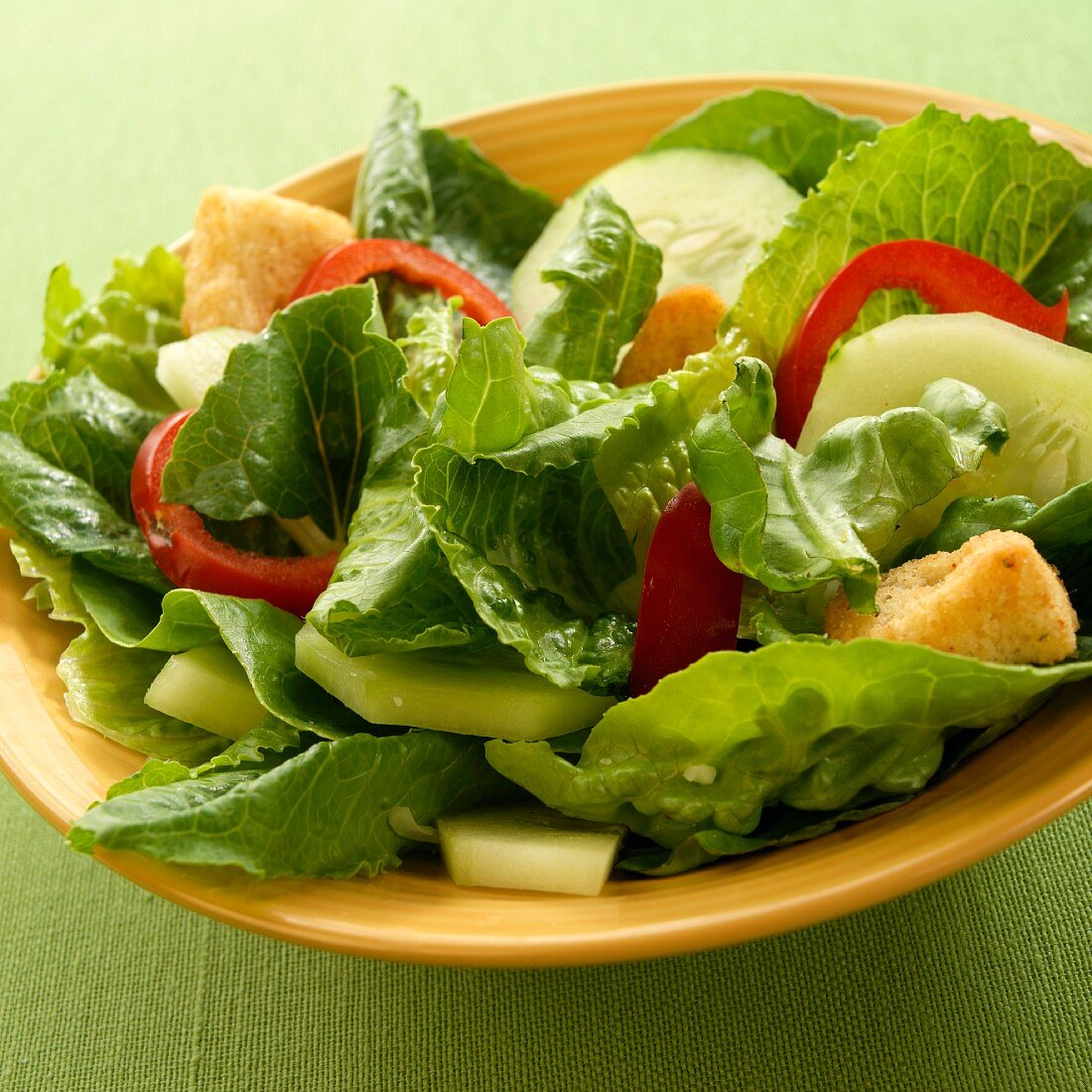 Simple Salad with Romain Lettuce, Cucumber, Red Pepper and Croutons; In a Yellow Bowl
