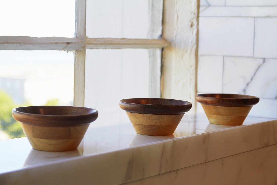 Three Wooden Bowls on Marble Ledge by Window