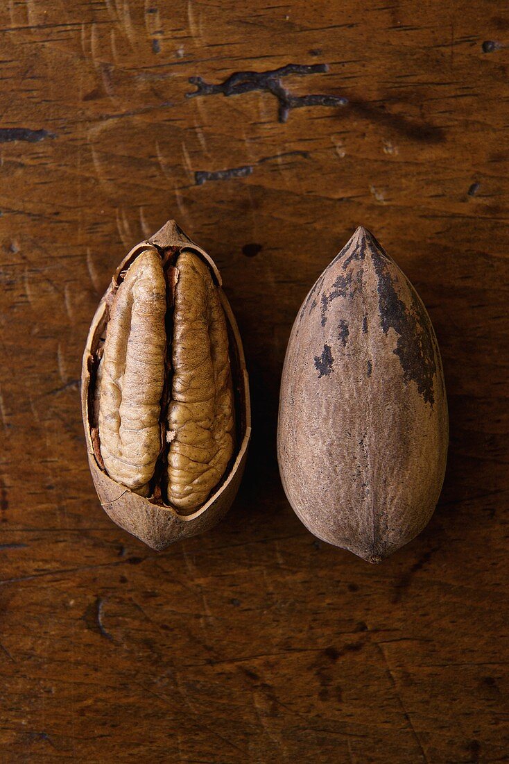 Cracked Pecan and Whole Pecan in Shell on Wooden Table
