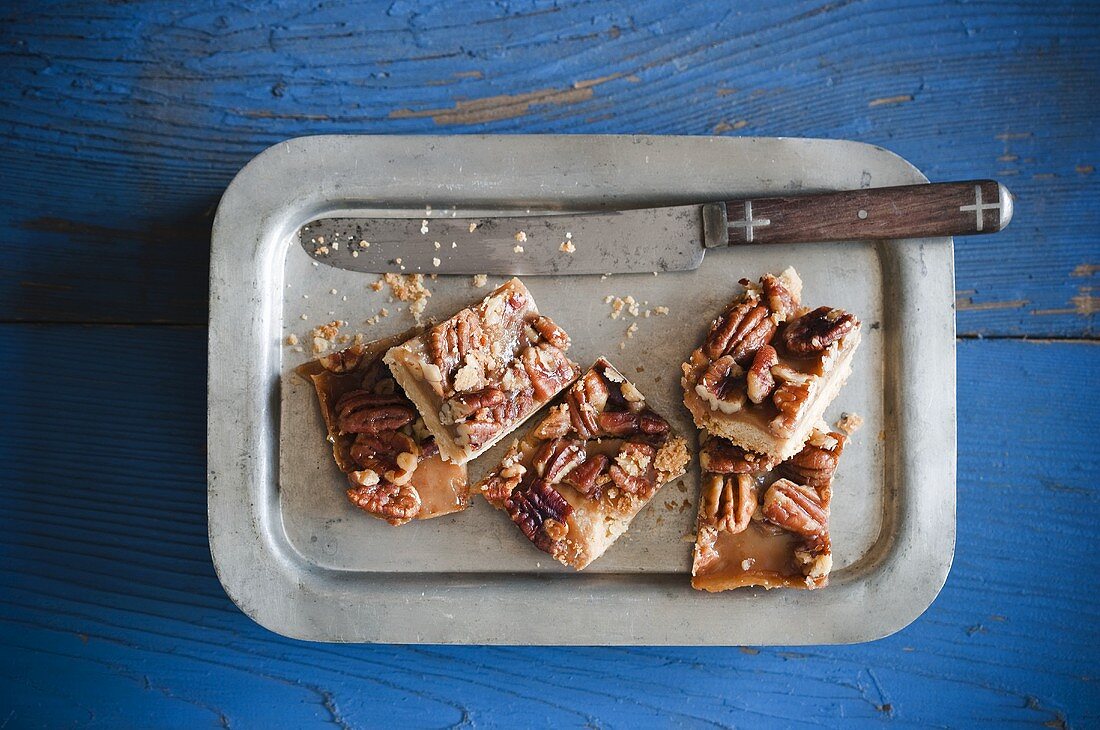 Pecan Squares on a Metal Plate; Knife