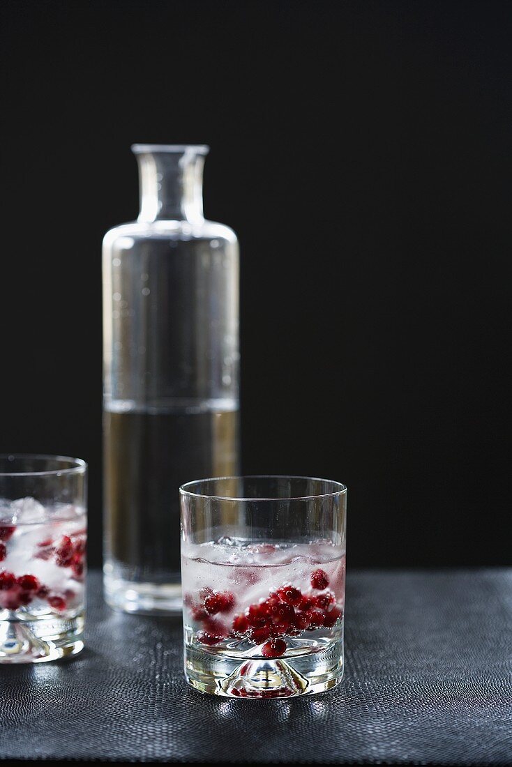 Drinks mit Wodka und Granatapfelkernen vor Wodkaflasche