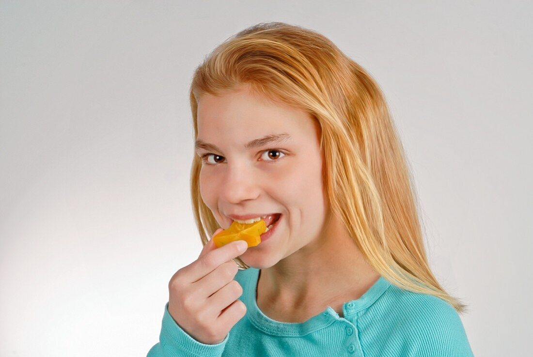 Girl Eating a Slice of Star Fruit