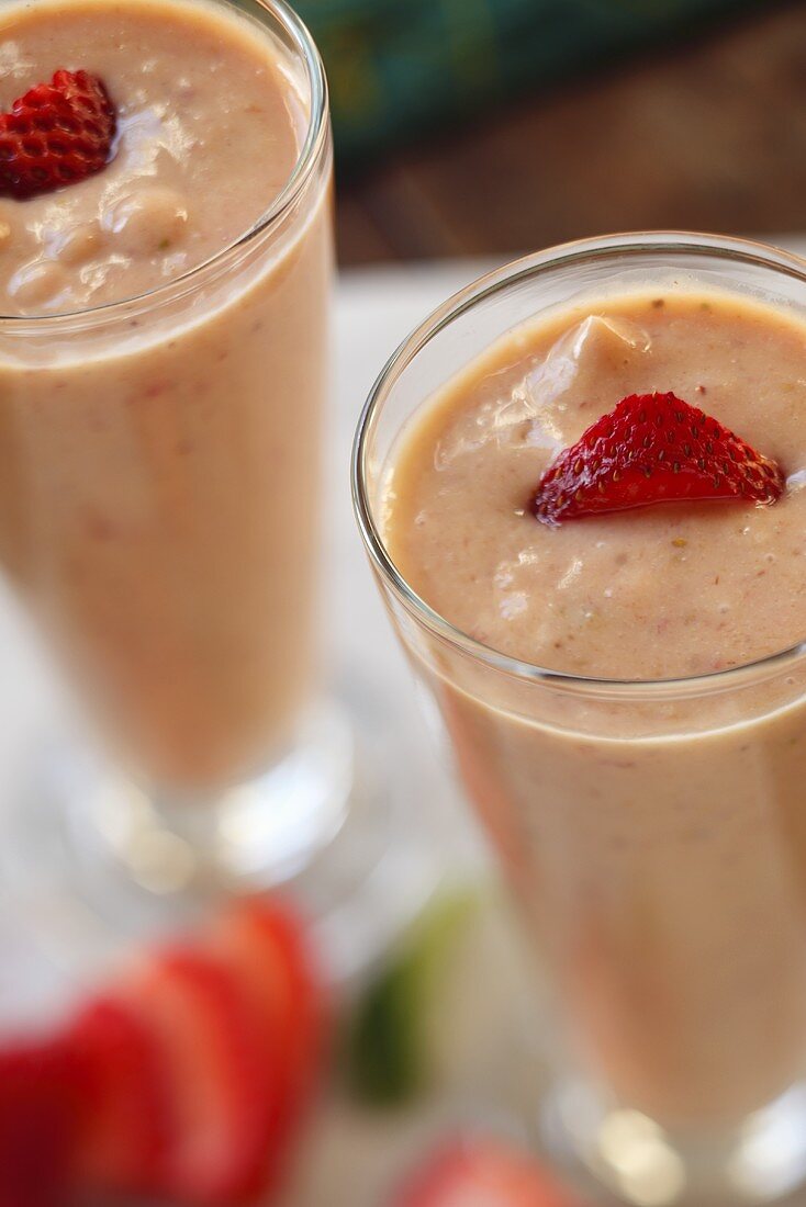 Two glasses of strawberry and mango smoothies with fresh strawberries