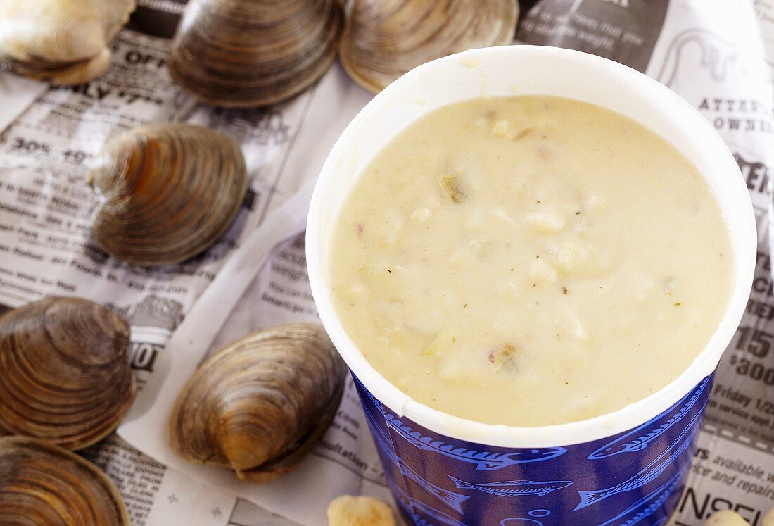 Clam Chowder in Paper To-Go Cup; On Newspaper with Fresh Clams