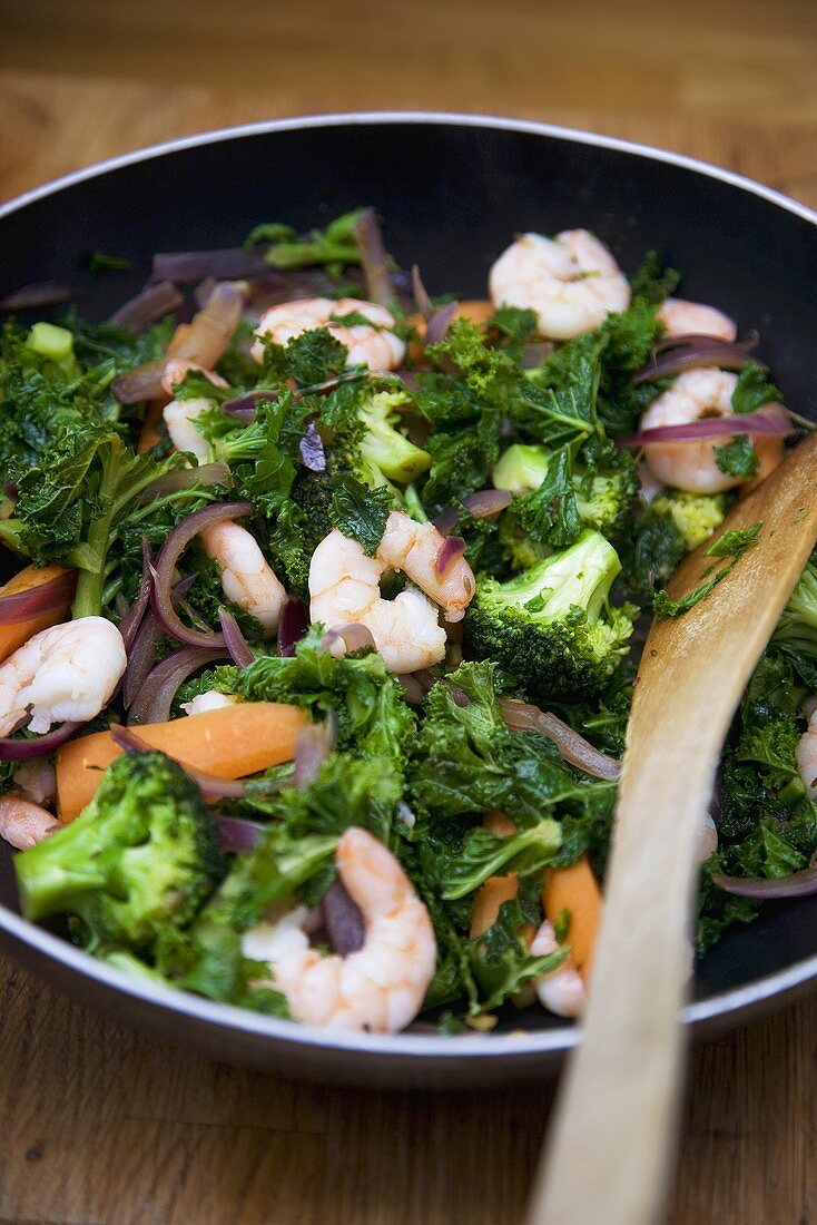 Shrimp Stir Fry with Broccoli on a Skillet; Wooden Spoon