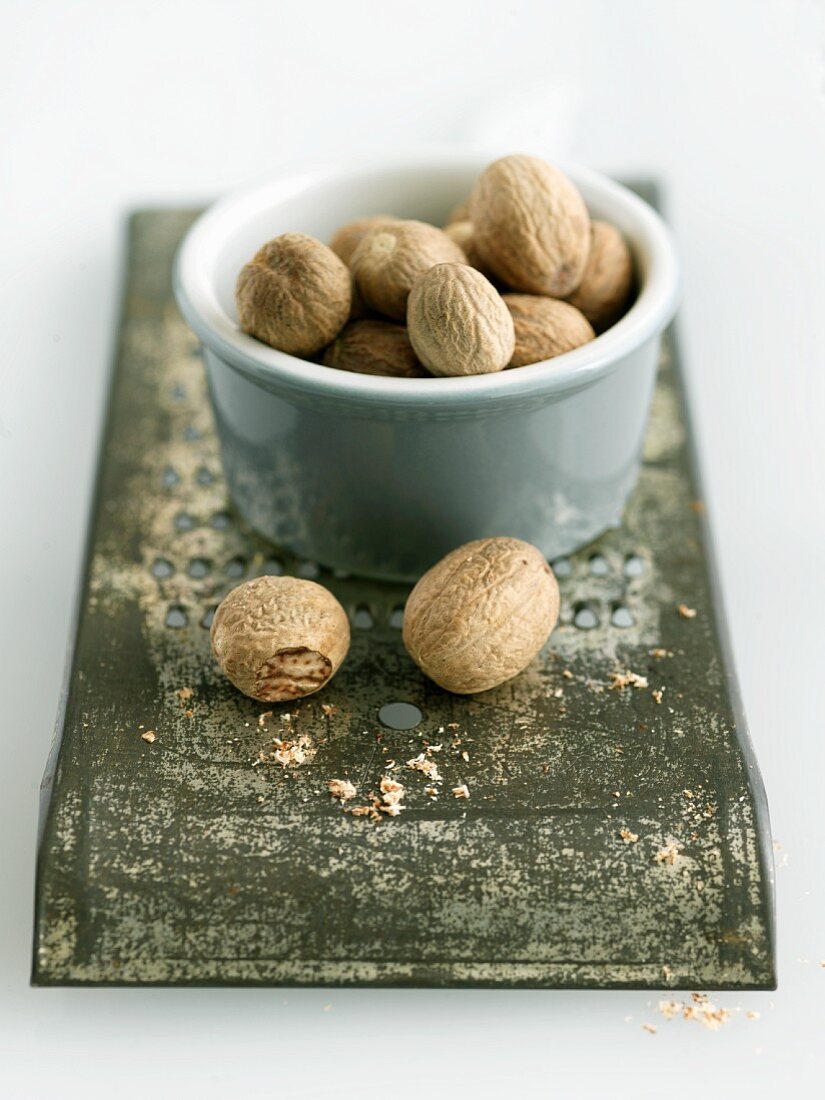 Bowl of Whole Nutmeg on Metal Grater