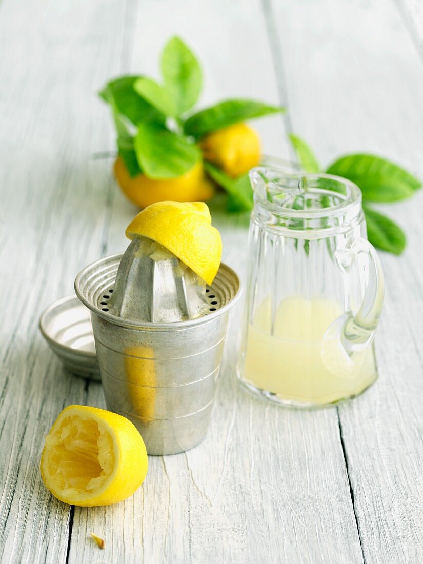 Zitronenpresse und Glaskrug mit frisch gepresstem Zitronensaft