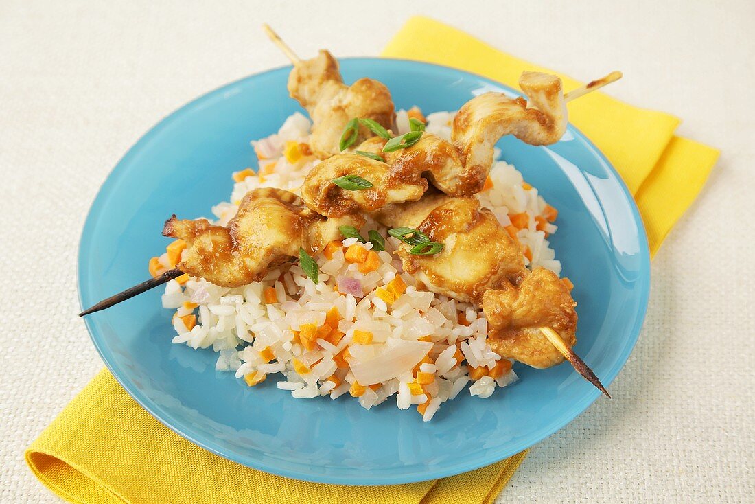 Turkey Skewers Over Rice with Carrots and Onions on a Blue Plate