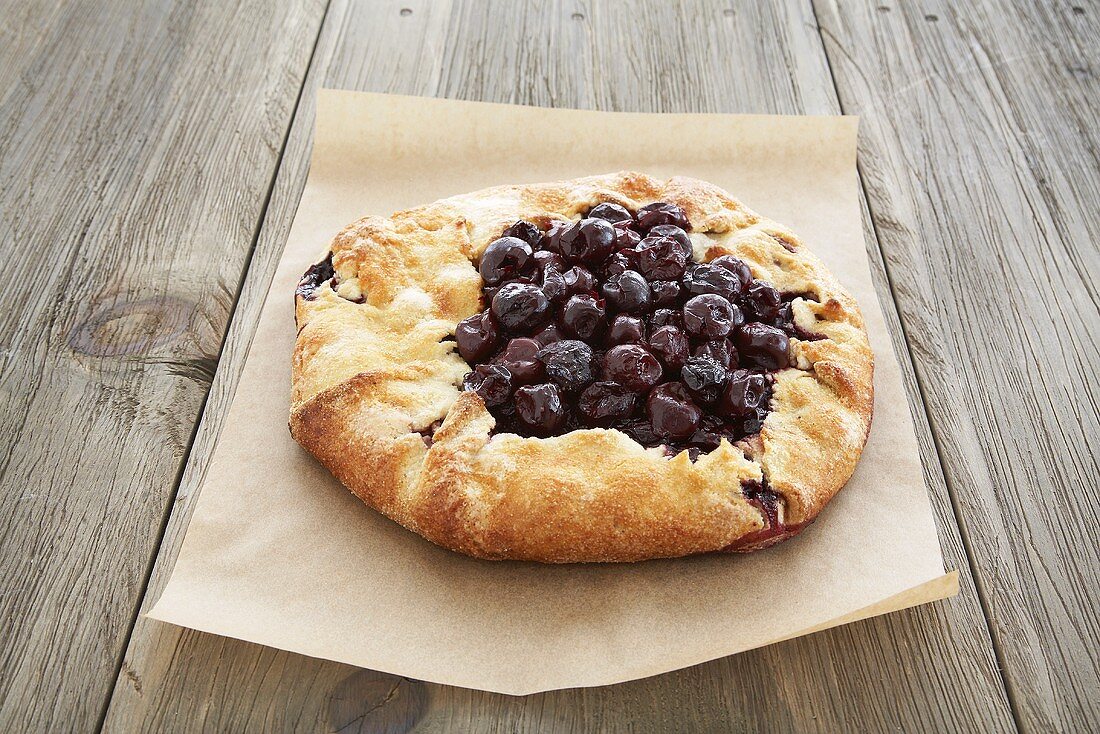 Rustic Cherry Pie on Paper on a Wooden Table