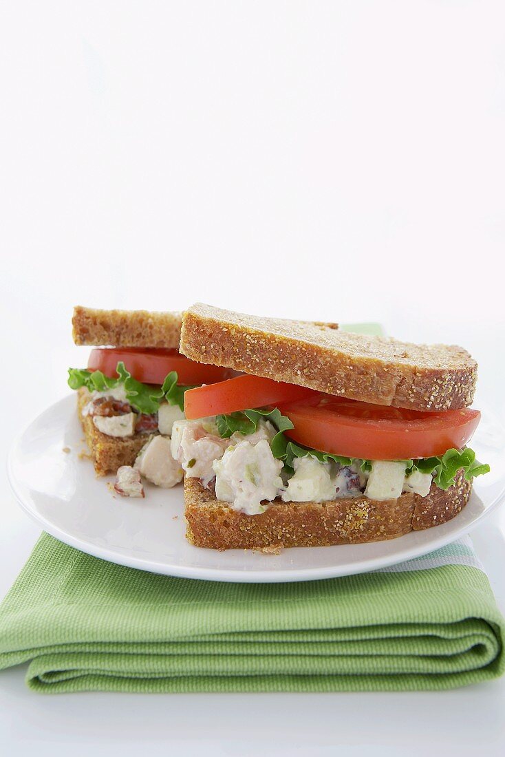 Chicken Salad Sandwich with Lettuce and Tomato on Wheat Bread; Halved on a Plate