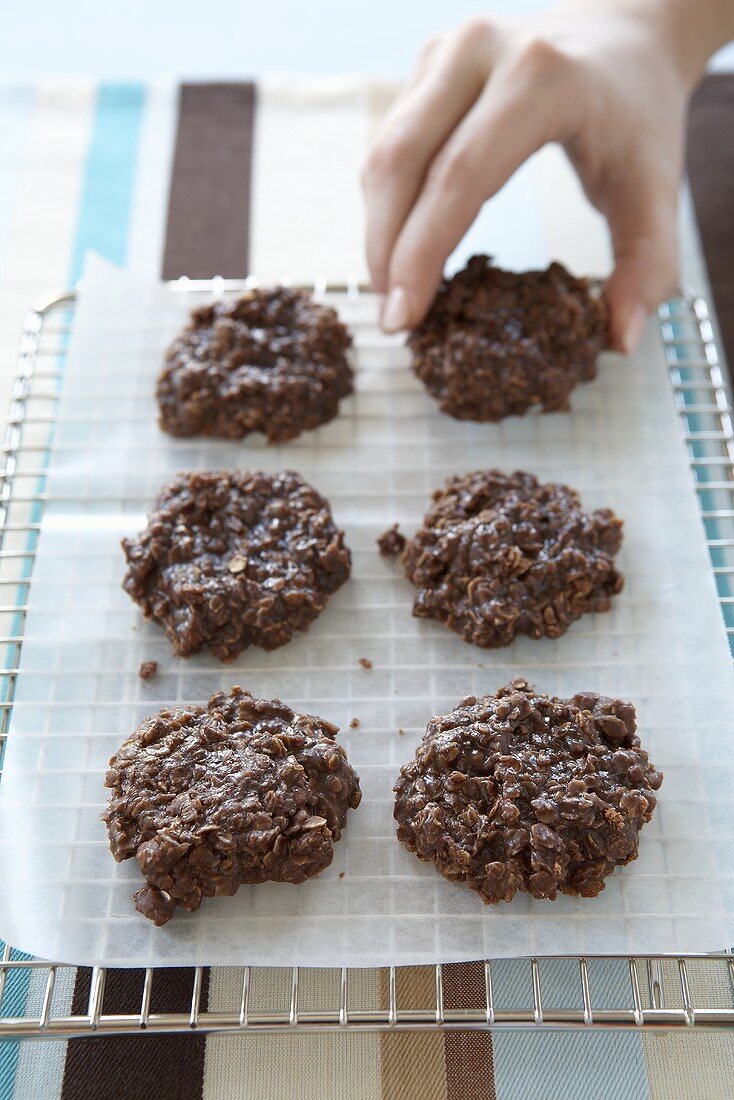 Hand Grabbing a Chocolate Oatmeal Cookie from Cooling Rack