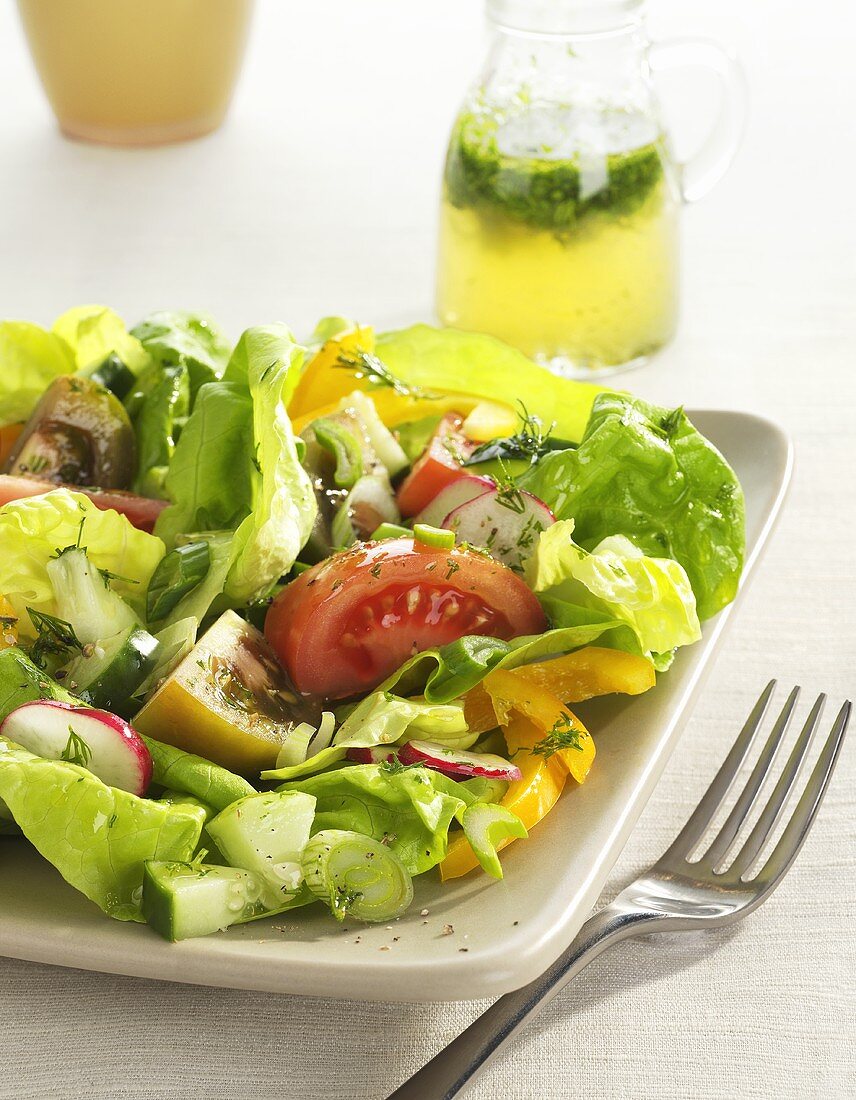 Salad Made with Butter Lettuce, Tomatoes and Radishes; Pitcher of Dressing