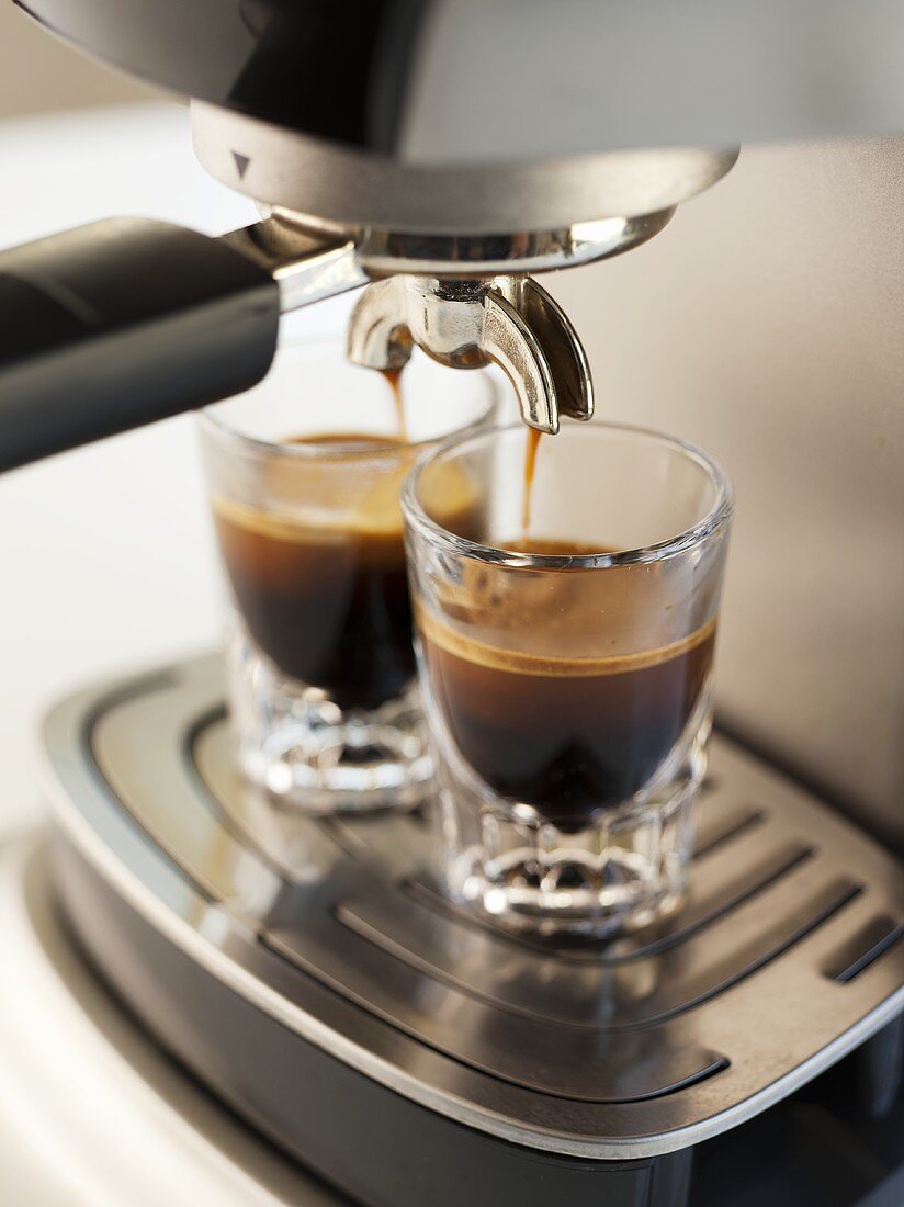 Espresso fliesst aus der Maschine in zwei Gläser