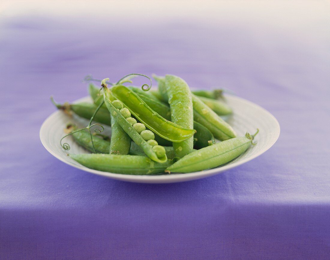 Fresh Pea Pods on a Plate; One Split Open to Show Peas
