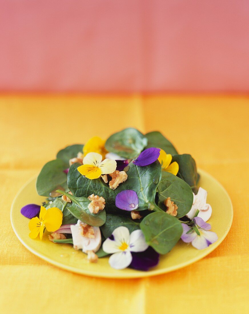 Spinatsalat mit Essblüten und Nüssen