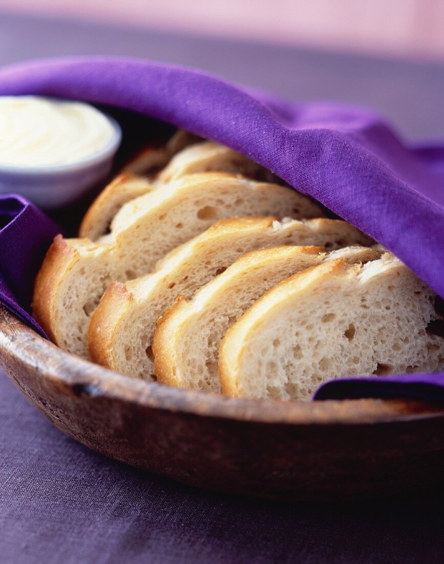 Sliced white bread in a wooden bowl covered with a cloth