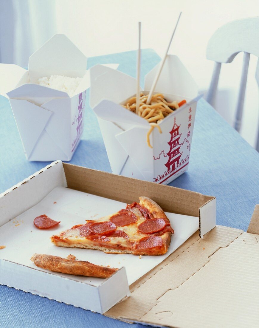 Assorted Take Out Food on a Table; Pizza and Chinese