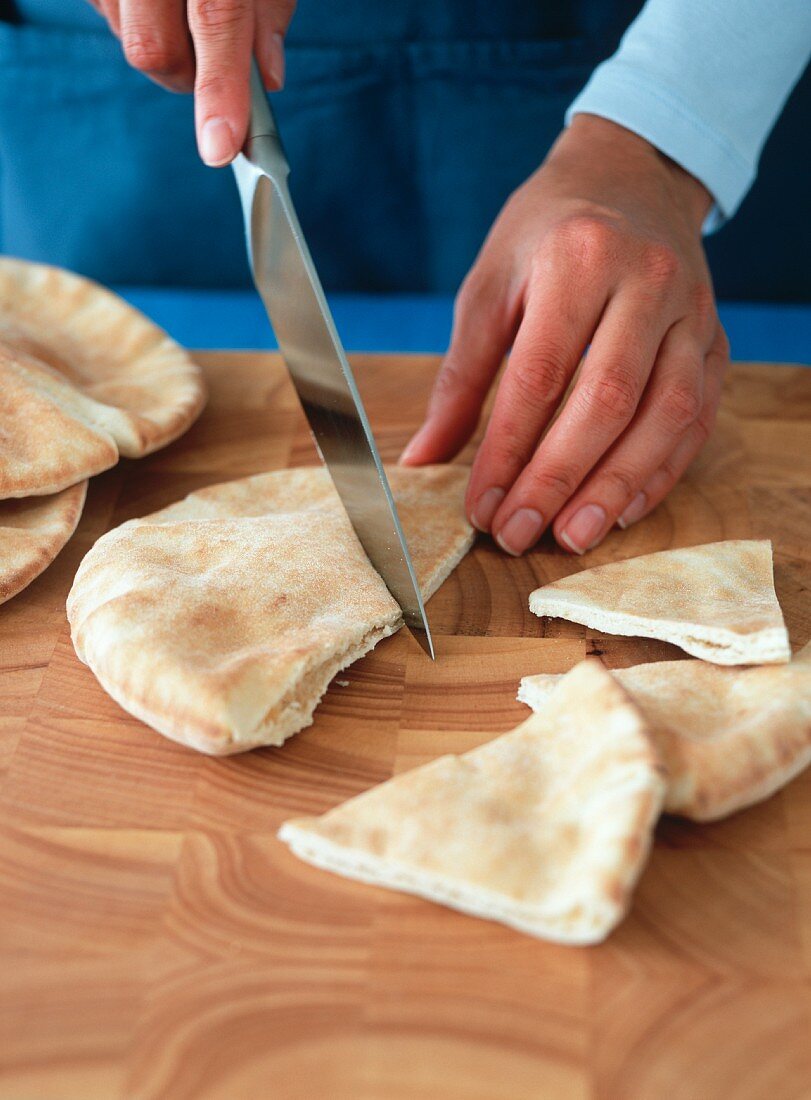 Person Slicing Pita Bread into Triangles