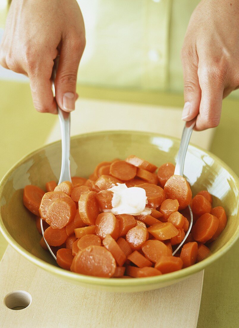 Karottenscheiben mit Butter in einer Schüssel vermischen
