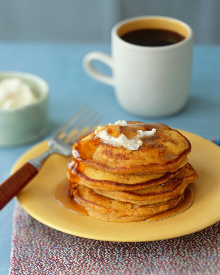Stack of Pumpkin Pancakes with Butter and Maple Syrup; Cup of Coffee