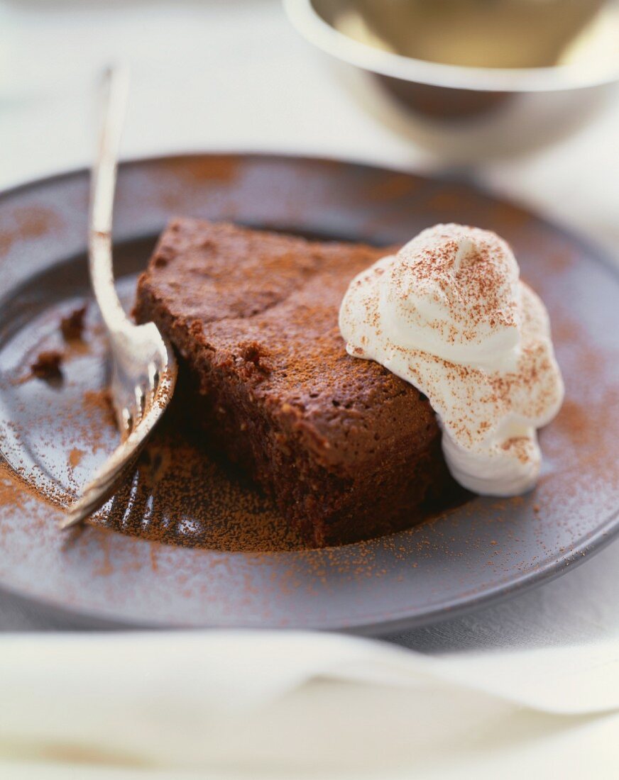 Mehlloser Schokoladenkuchen mit Schlagsahne und Kakaopulver