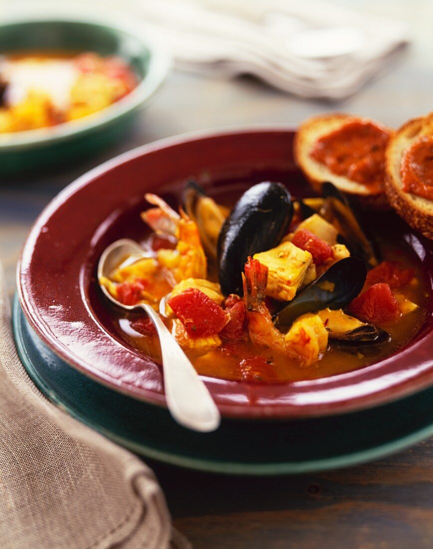 Bowl of Seafood Bouillabaisse with a Spoon and Bread