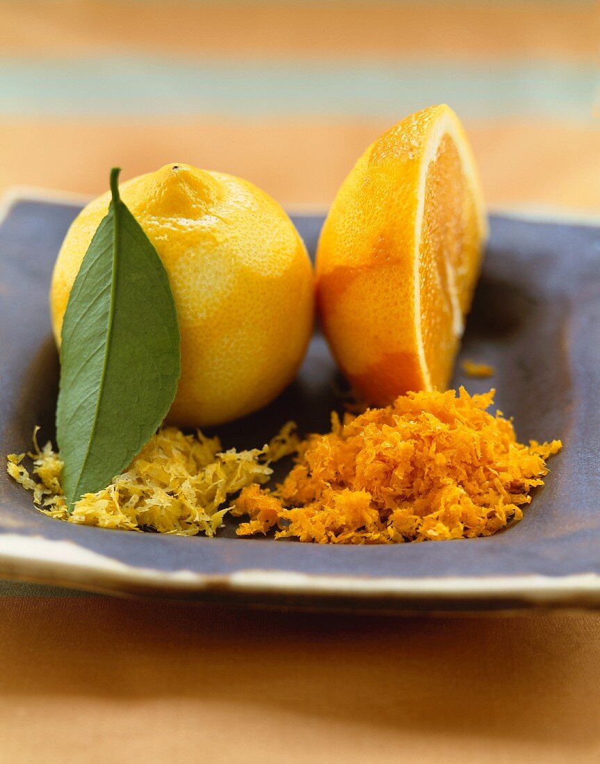 A Lemon and Orange with Grated Lemon and Orange Rinds on a Dish