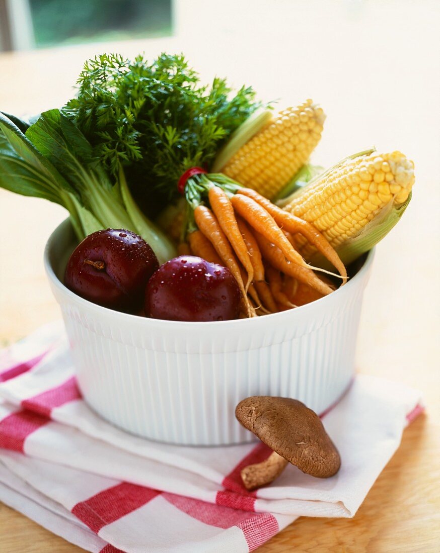Frisches Gemüse, Obst und Maiskolben in Schüssel auf Geschirrtuch
