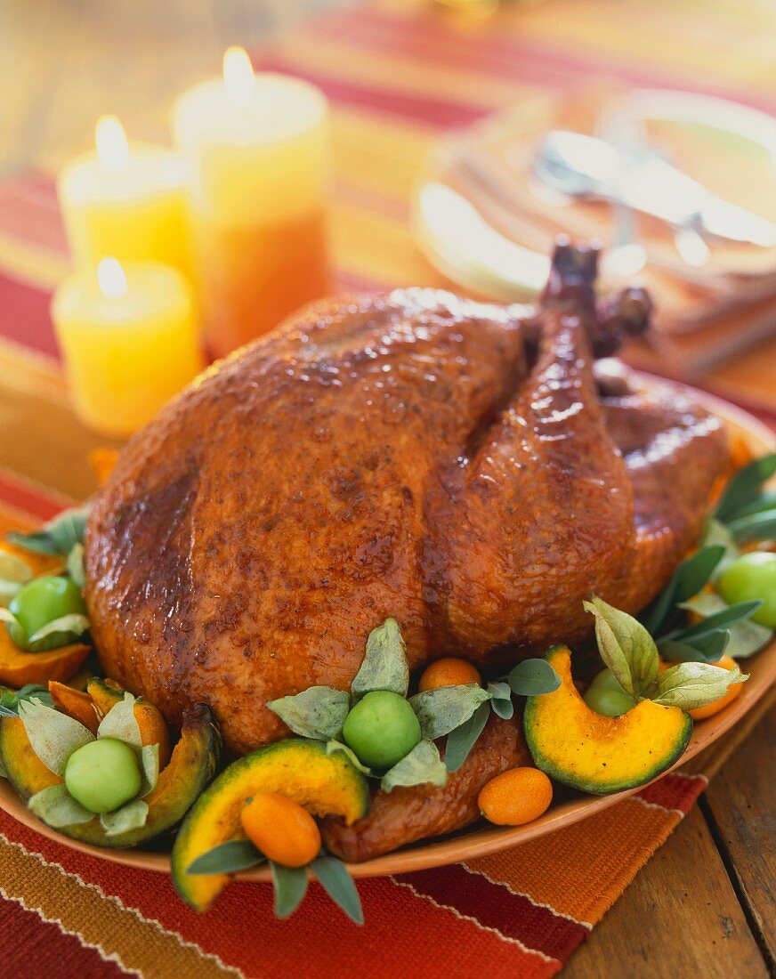 Whole Roast Turkey on a Platter with Squash and Kumquats; On a Table with Candles