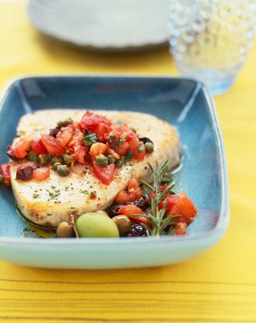 Swordfish Fillet Topped with Tomato and Caper Sauce; In a Blue Bowl
