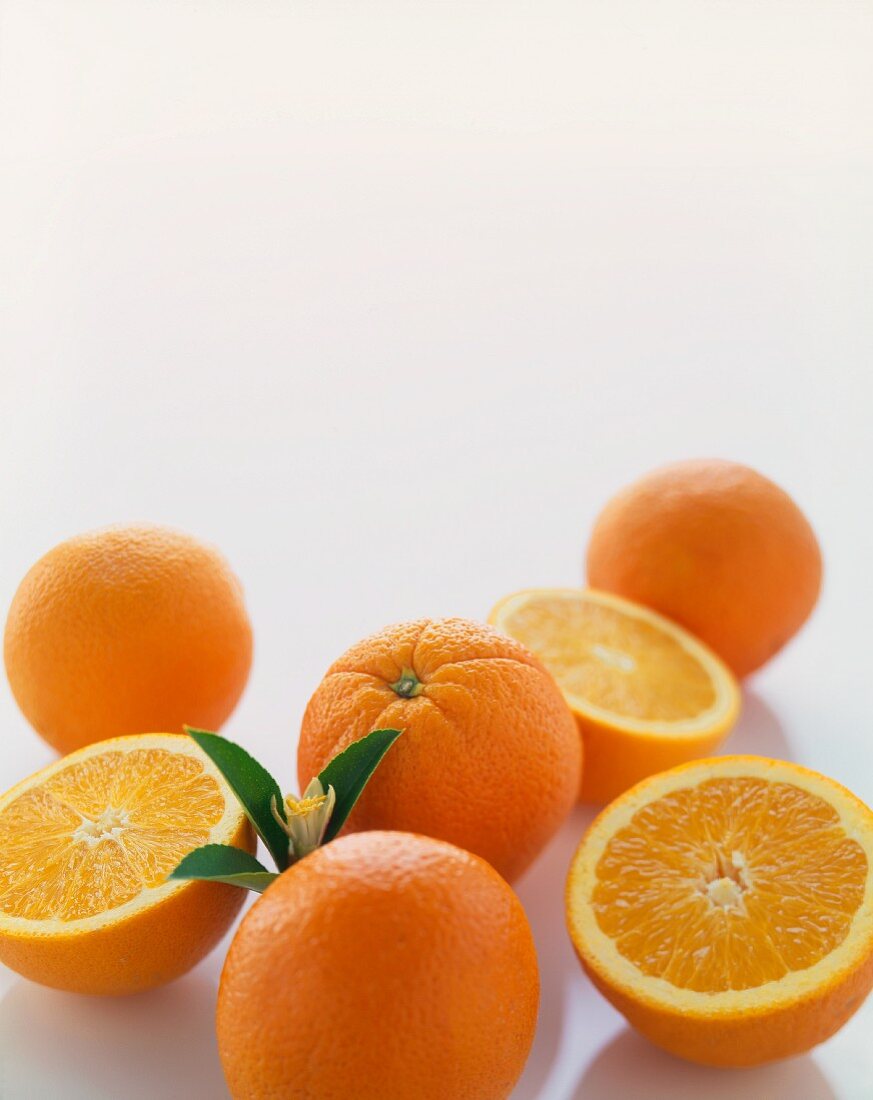 Mehrere Orangen, ganz und halbiert