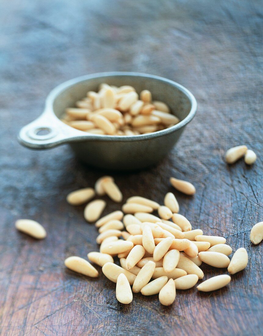 Pine nuts in a measuring cup and on a chopping board