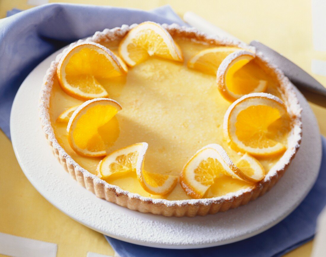 An orange and vanilla tart with icing sugar