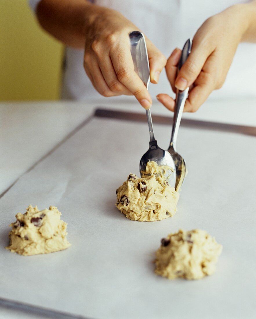 https://media01.stockfood.com/largepreviews/MjE2MDEyOTY=/00696816-Placing-Chocolate-Chip-Cookie-Dough-onto-a-Baking-Sheet.jpg