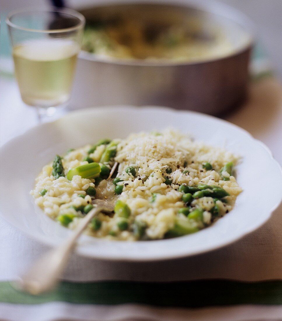 Risotto with green asparagus and peas served with a glass of white wine