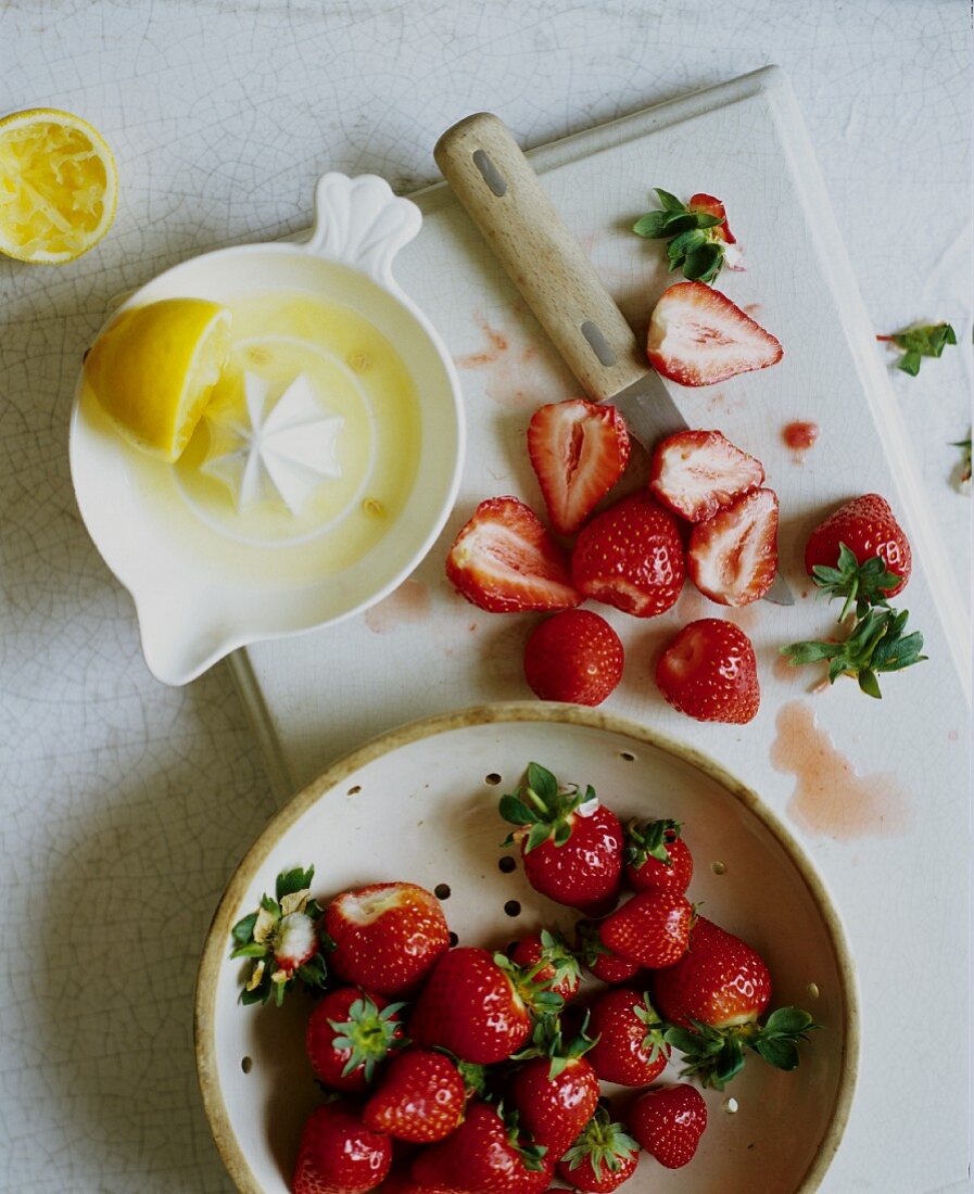 Frische Erdbeeren, teilweise geputzt und ausgepresste Zitrone