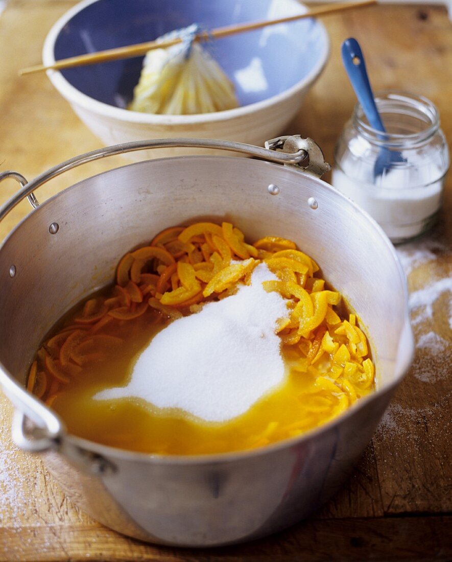 Orangenmarmelade zubereiten: Orangenschale mit Zucker in ein einem Topf