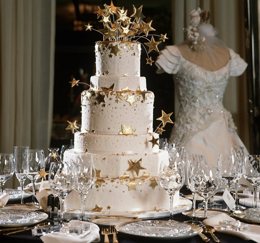 Mehrstöckige Hochzeitstorte mit goldenen Sternen auf festlich gedecktem Tisch