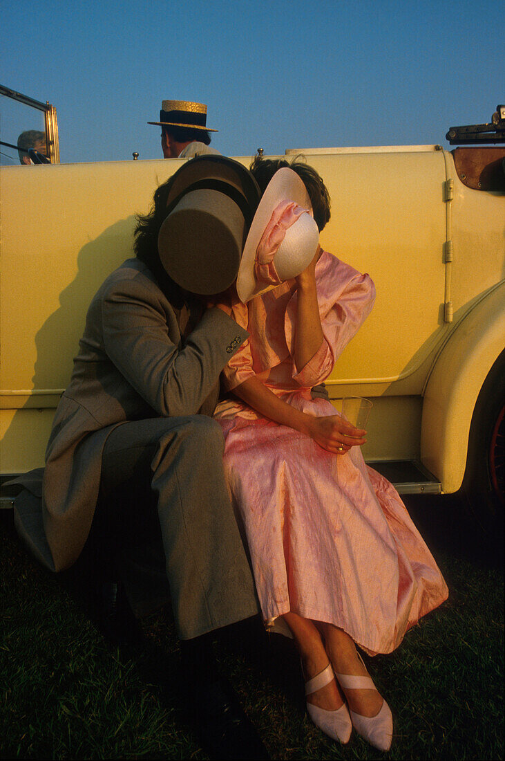 Couple kissing each other in front of vintage car, Ascot, England, UK