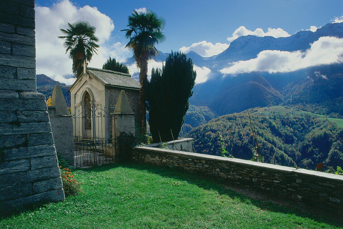 Small chapel with palm trees in front of mountains, Verda, Centovalli, Ticino, Switzerland