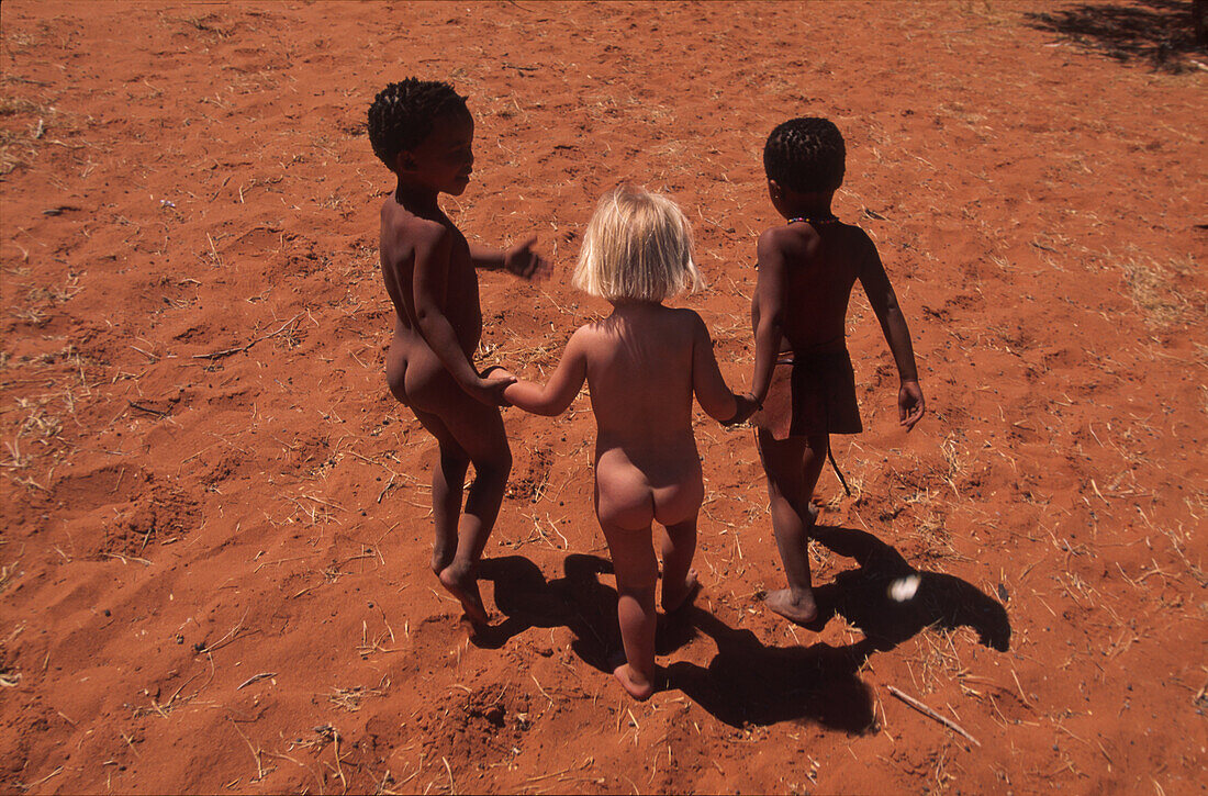 Einheimische Kinder und ein blondes Mädchen im Sonnenlicht, Namibia, Afrika