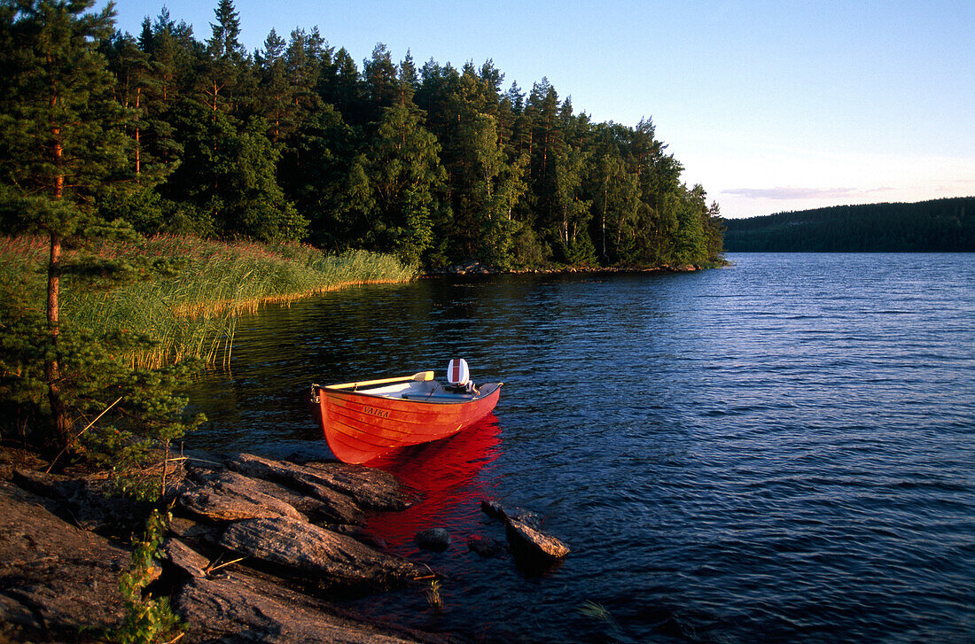 Ein Boot liegt am Ufer in der Abendsonne, Västergötland, Schweden