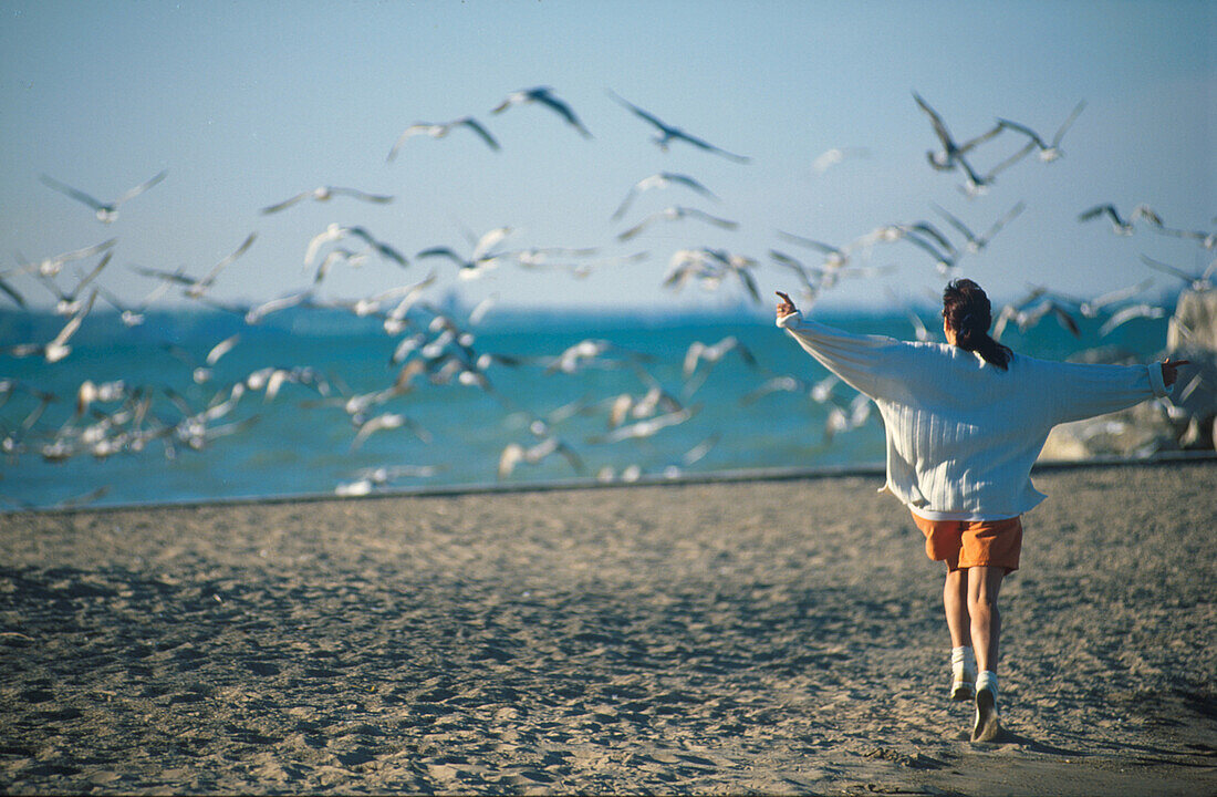 Girl running along the beach chasing seagulls, Lake Michigan, USA