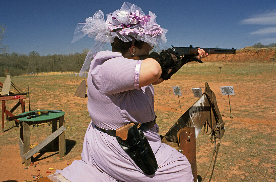 Frau im eleganten Kleid zielt mit einem Gewehr, Route 66, Oklahoma, USA