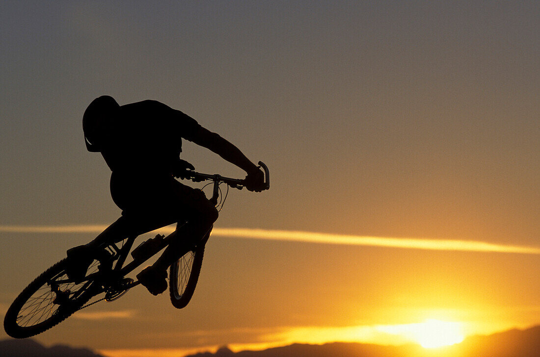 Mountainbiker beim Sprung, Sonnenuntergang