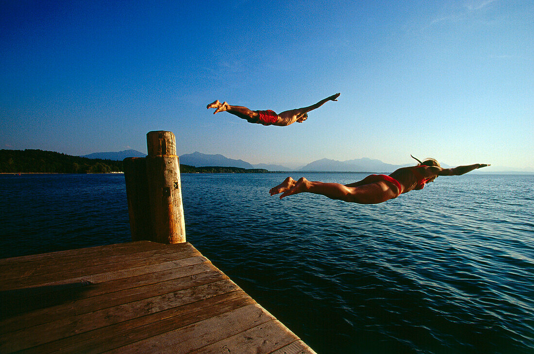 Man and women jumping in lake, Chieming, Chiemsee, Upper Bavaria