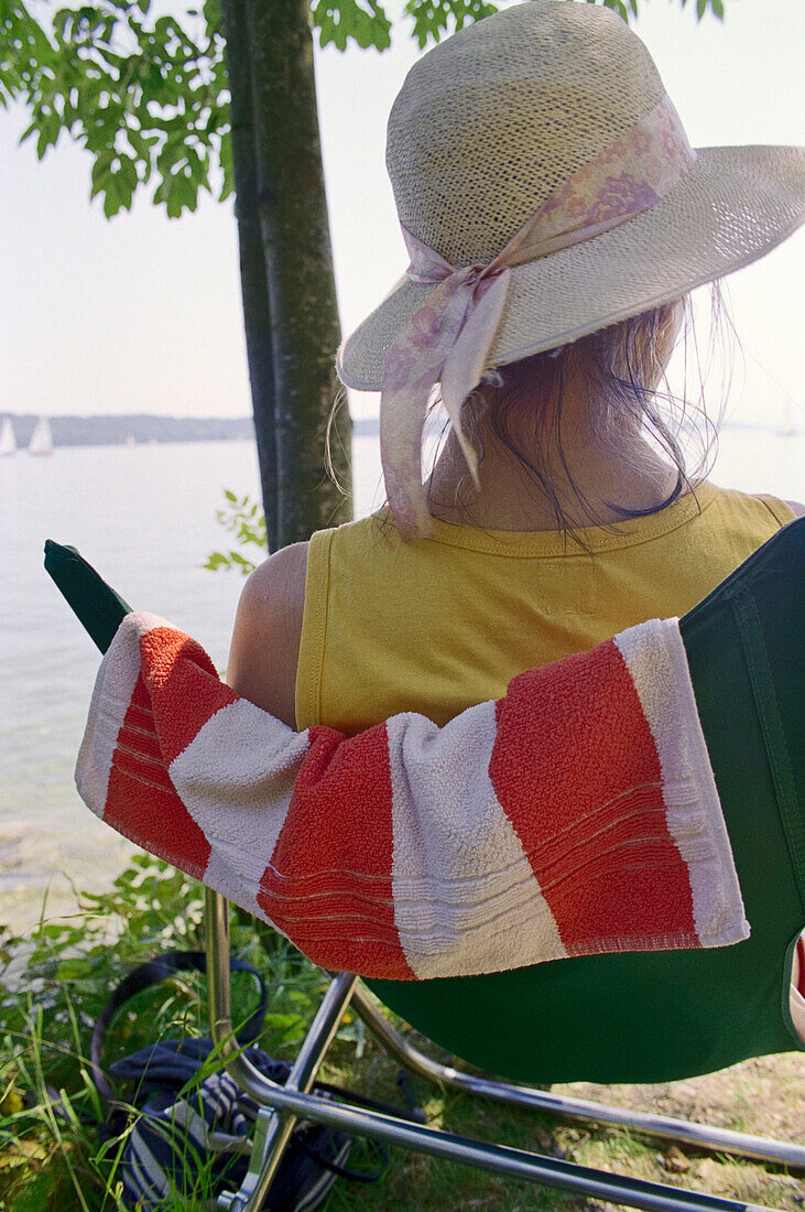 Junge Frau mit Sonnenhut im Liegestuhl, Starnberger See, Bayern, Deutschland