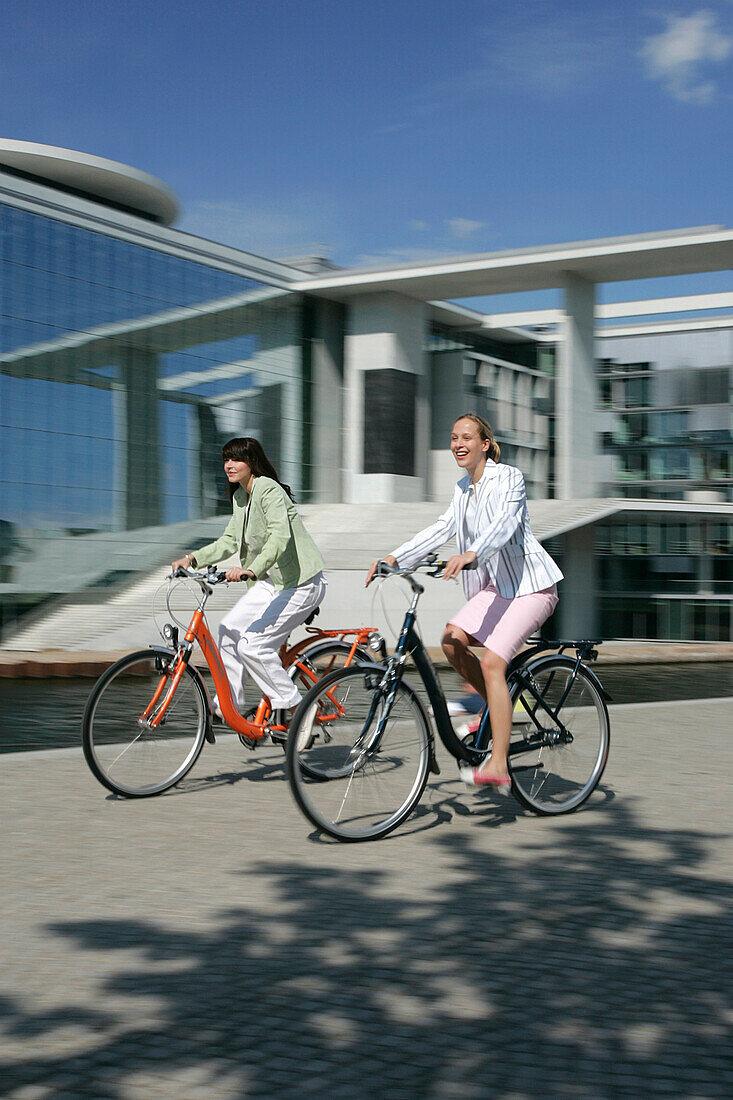 Two young women cycling cross-town, Berlin, Germany