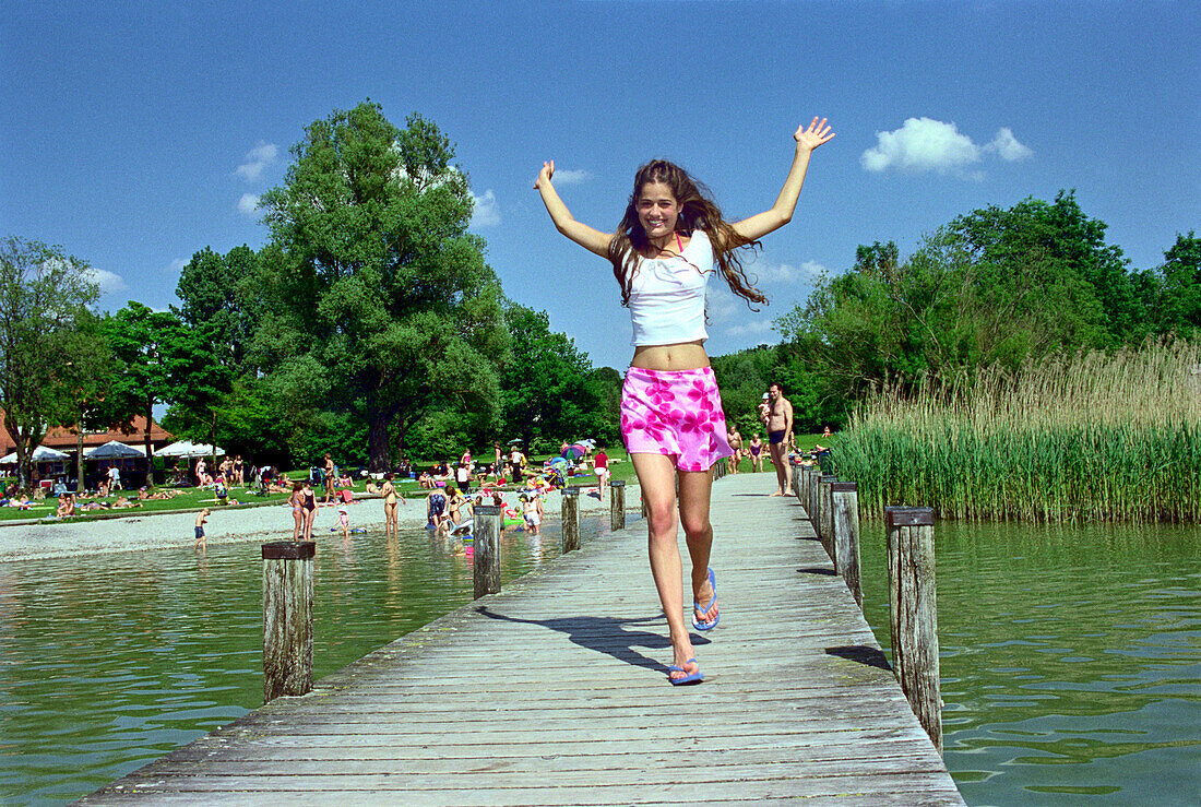 Young woman jumping on a jetty, Starnberger See, Bavaria, Germany